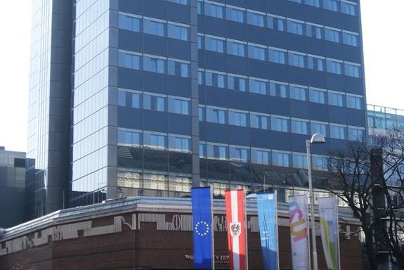 Plus-Energie Bürohochhaus Straßenblick: Sockelbereich im Vordergrund ist aus Ziegel, im Hitergrund ist das Hochhaus.