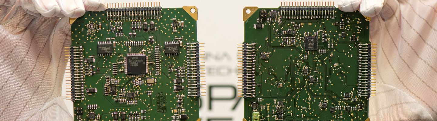 Zwei große Computerchips werden von Händen in Baumwollhandschuhen in die Kamera gehalten