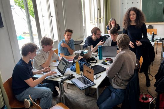 Mehrere Studierende sitzen um einen Tisch und diskutieren