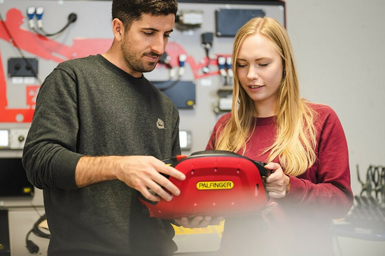 A man and a woman holding an electronic case labelled Palfinger