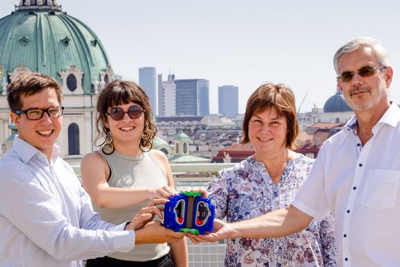 Vier Personen mit Modell eines Fusionsreaktors, im Hintergrund die Wiener Karlskirche