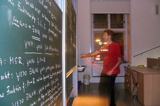 One person writes formulas on the board