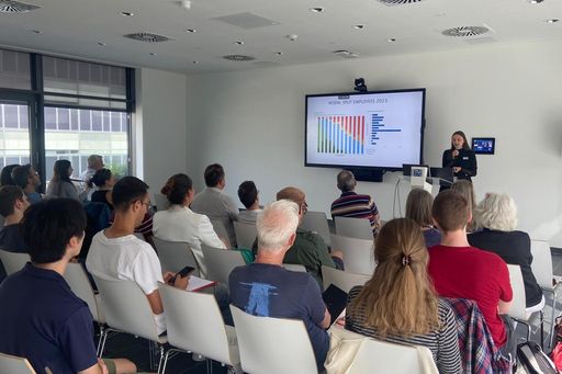 Publikum sitzend von hinten, Sprecherin bei Podium