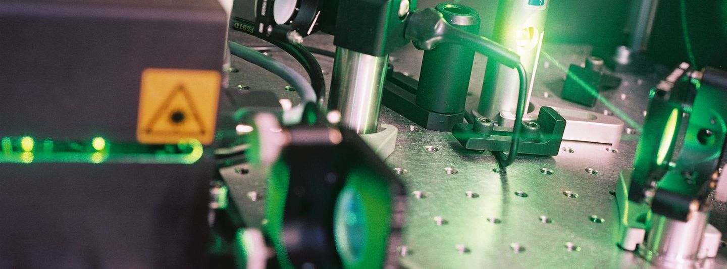 Links ist ein größere Gerät platziert, links ist ein Laser. Dazwischen liegen mehrere Kabel und andere Teile.