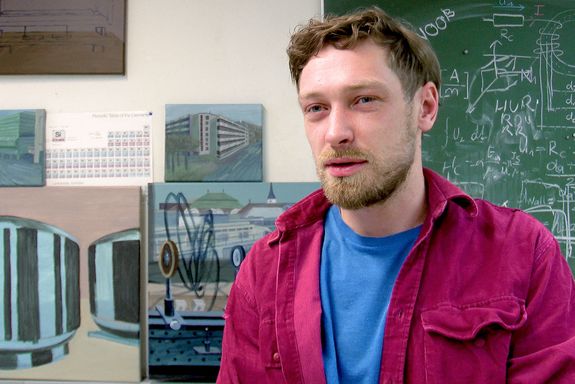 Ivan Chemakin vor einer Tafel und seinen Bildern