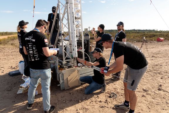 mehrere Personen rund um eine mehrere Meter lange Rakete