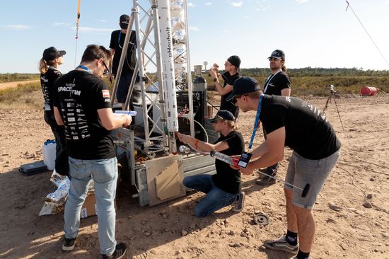 mehrere Personen rund um eine mehrere Meter lange Rakete