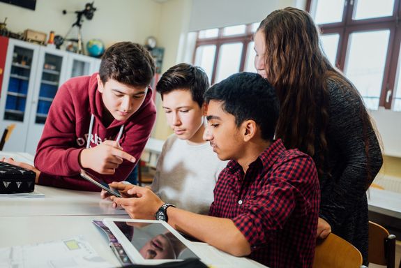 Jugendliche erarbeiten ihr Projekt gemeinsam am Tablet.