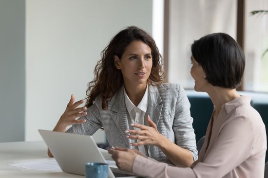 Two women are sitting together at a table and talking.