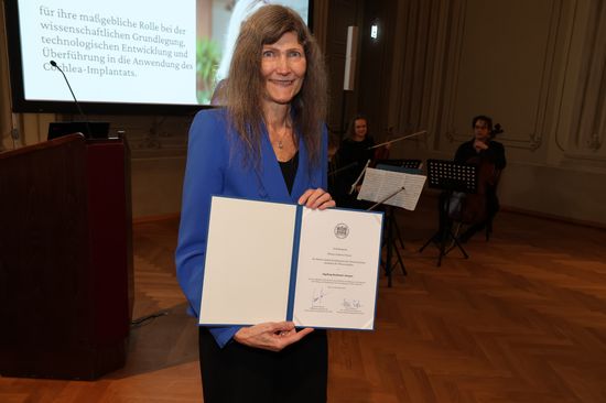 Ingeborg Hochlager-Desoyer hält lächelnd die Urkunde in die Kamera