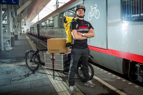 Mann mit Lastenfahrrad vor einem Zug