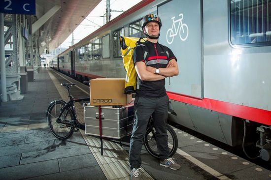 Mann mit Lastenfahrrad vor einem Zug