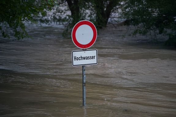 Verkehrsschild mit Aufschrift "Hochwasser" an einer überfluteten Straße