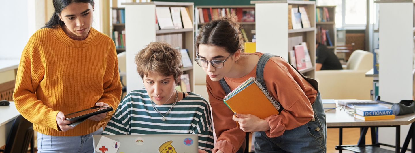 Eine Gruppe an Studierenden sitzt vor einem Laptop und wird beraten.