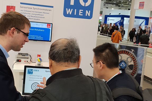 A TU Wien research member explaining the sensorless synchronous motor to visitors at the TU Wien stand.