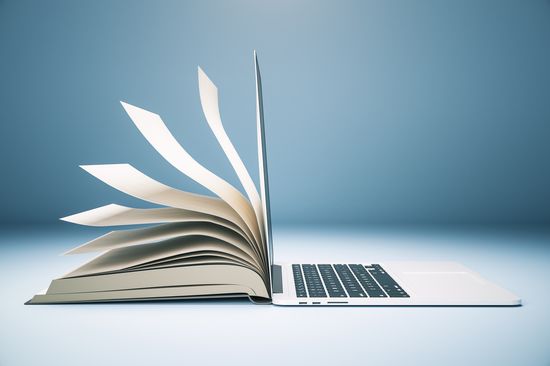 Ein aufgeschlagenes liegendes Buch lehnt mit dem rechten Buchrücken gegen einen aufgeklappten Laptop, blauer Hintergrund