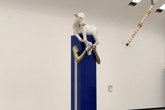 blaue Säule, darauf Kalb in weiß und Hände in gold und weiß