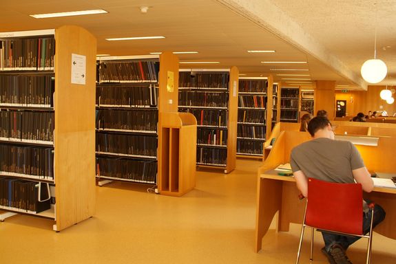 Bibliothek innen Das Bibliotheksgebäude von ihnen mit mehreren Bücherreihen und Arbeitsplätzen.