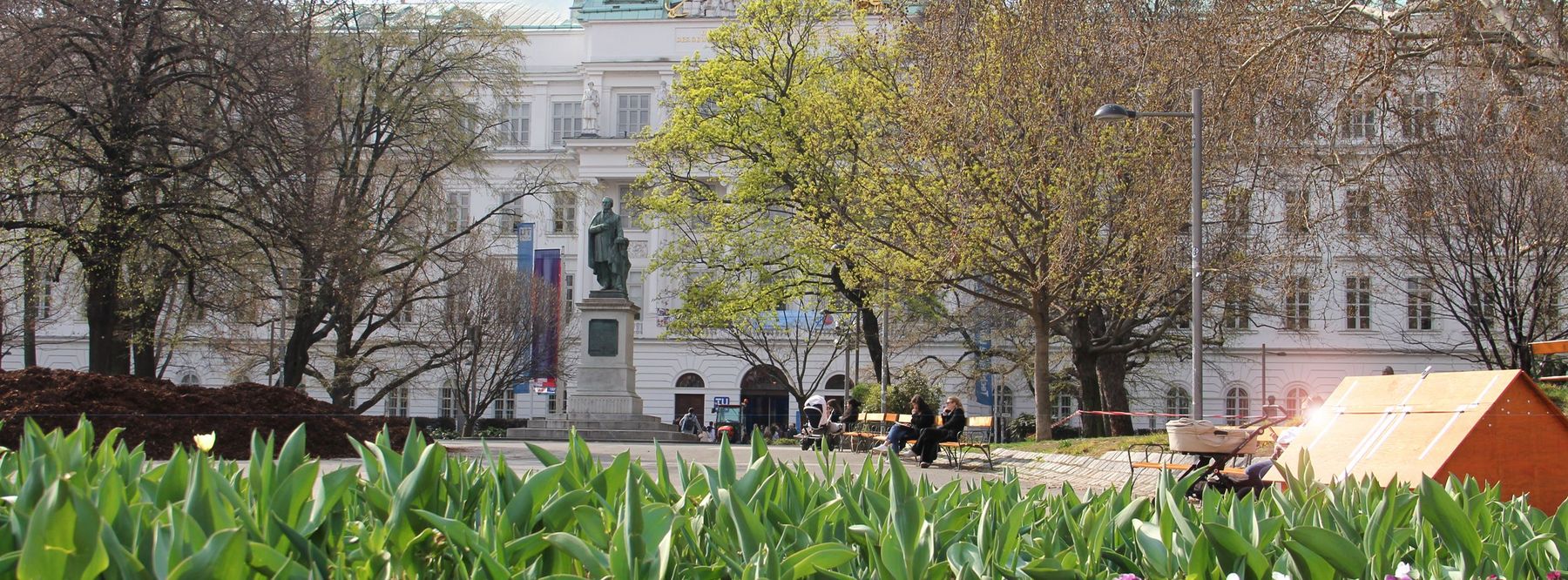 Im Hintergrund das Hauptgebäude der TU Wien, im Vordergrund ein buntes Blumenbeet