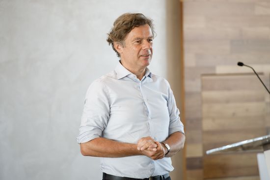 Wolfgang Güttel am Podium, Hintergrund Wand, rechts vorne Pult mit Mikrofon