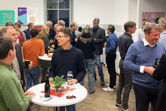 Mehrere Menschen stehen in Gruppen zusammen und unterhalten sich.