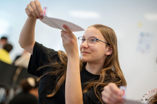 Mädchen visualisiert mit einem Stück Papier ein mathematisches Problem