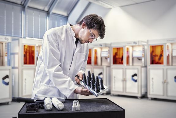 Labor mit 3D-Druckern im Hintergrund und Entwickler im Vordergrund.