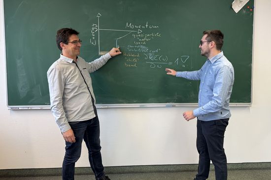 Two researchers in front of a blackboard