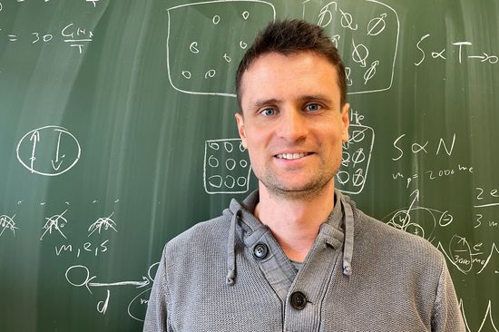 Portrait of Andrej Pustogow in front of a blackboard.