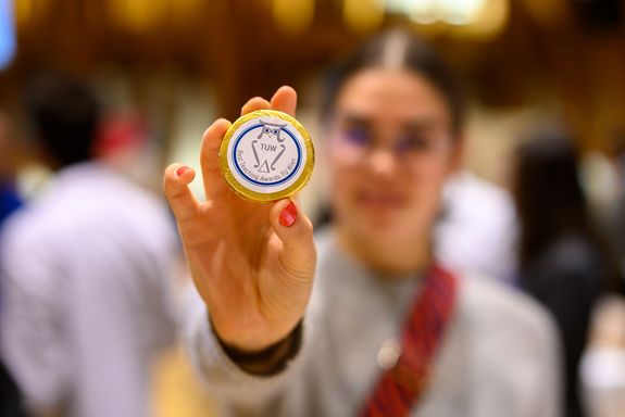 Person hält Schokotaler in die Kamera, Person und Hintergrund sind unscharf