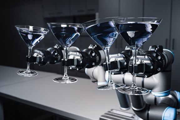 Roboterarm hält Cocktailglas in der Hand.