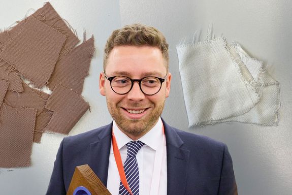 Emanuel Boschmeier bei der Verleihung des INI-Preises, dahinter Textilproben, bearbeitet mit den neuen Recycling-Methoden.