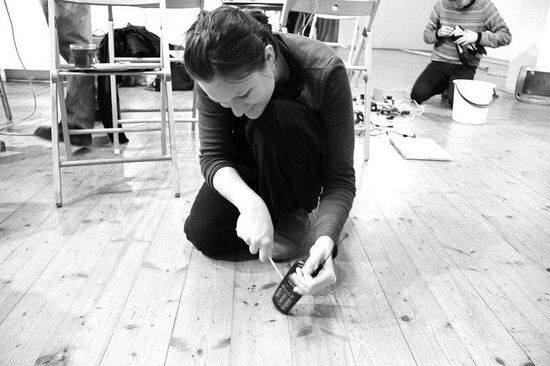 Eine Frau beschäftigt sich mit einem Handy am Boden.