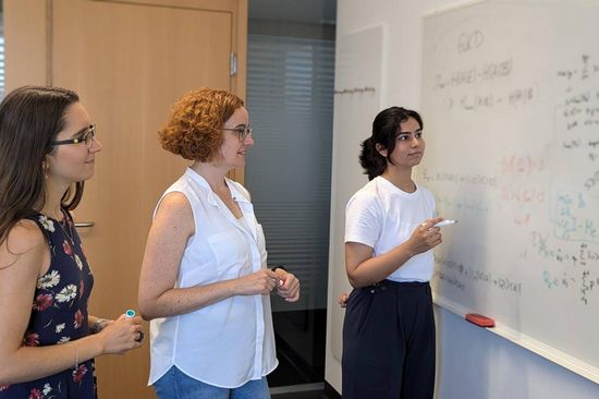 Three women in front of a whiteboard