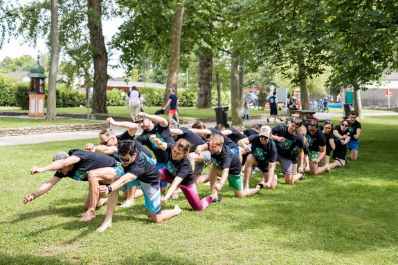 Menschen im Gras bei Aufwärmübungen kniend