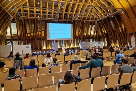 Kuppelsaal: beim Vortrag, Sprecher auf Bühne und Zuhörer_innen sitzend von hinten