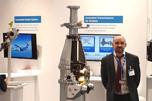 Florian Donner (TU Wien) beside a helicopter drivetrain