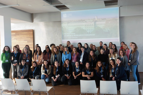 Group picture of the femTUme Congress participants in the TUtheSky event room. Screen in the background.