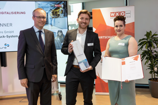 CEO Dr. Robert Gmeiner und Kathrin Wallner präsentieren eine Flasche Sekt und die MERCUR-Urkunde.