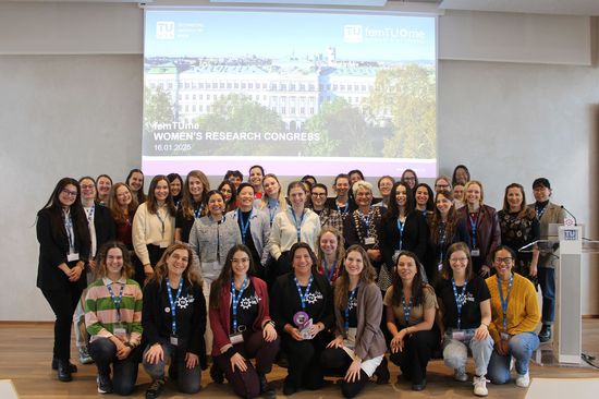 Group photo of the femTUme conference participants in front of a screen