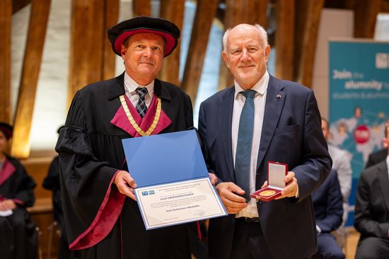 Ronald Blab und Josef Eberhardsteiner stehen nebeneinander. Blab hält eine Urkunde in der Hand, Eberhardsteiner die Medaille.