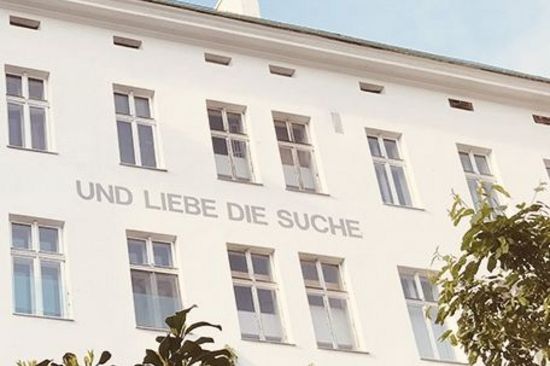 Hausfassade mit der Aufschrift: "Suche die Liebe und liebe die Suche"