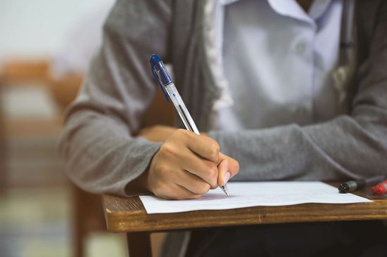 Großaufnahme Studierender sitzend mit Stift bei Prüfung, Kopf ist nicht zu sehen