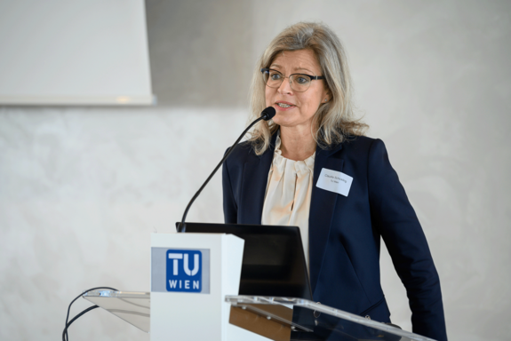 Claudia Schickling am Redner_innenpult. Sie trägt ein dunkles Jackett und eine helle Bluse.