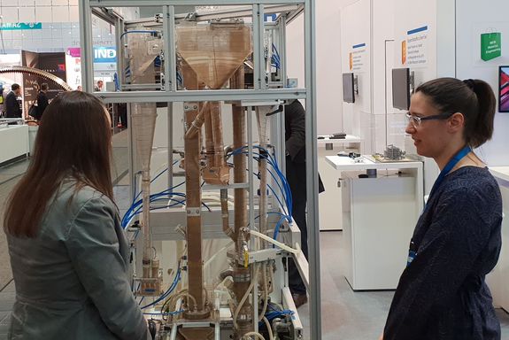 Julia Hofbauer explains the dual-fluid-bed gasification to a visitor in front of the model of the plant.