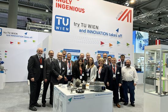 Gruppenfoto von Vetreter_innne der TU Wien, die am Messestand stehen. Im Hintergrund ist das Logo der TU Wien zu sehen.