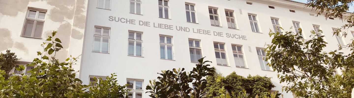 Hausfassade mit der Aufschrift: "Suche die Liebe und liebe die Suche"