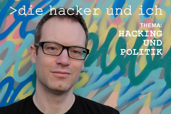 Porträt Marco Squarcina in schwarzem T-Shirt. Hintergrund Graffiti mit blauen, gelben, grünen, rosa Linien.