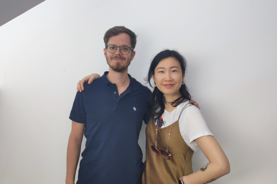 The photo shows Suvini and Lukas standing in front of a white wall.