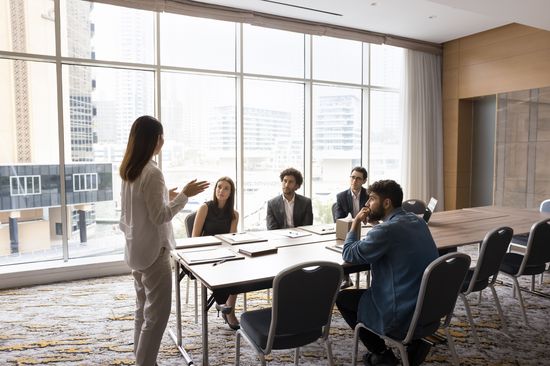 A woman is speaking in an office in front of several people.